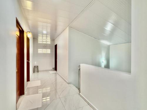 un corridoio con pareti bianche e un grande specchio di Spacious 2 Storey Homestay Tanjung Bungah 25Pax by 3C a Tanjung Bungah
