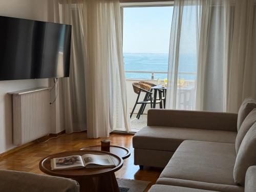 a living room with a couch and a large window at Zeusbnb Penthouse Sea View in Thessaloniki