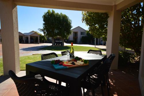 a table with a plate of fruit and a bottle of wine at Pelican Shore Villa 11- Kalbarri WA in Kalbarri
