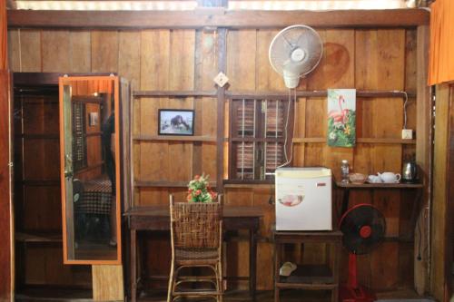 a room with wooden walls and a desk and a fan at Fish Island Bungalows in Kampot