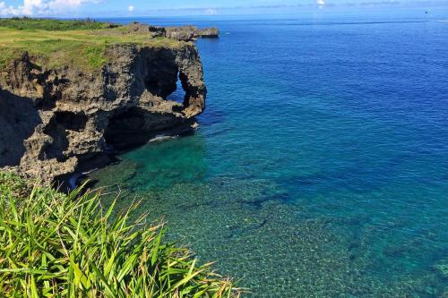 a cliff sticking out of the water near the ocean at Kahoo House in Nago