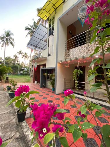 ein Haus mit rosa Blumen davor in der Unterkunft Mud apples varkalaa in Varkala