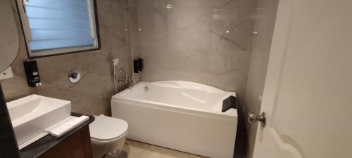 a bathroom with a white tub and a toilet and a sink at Pushpam Sanskruti Resort Karjat- Pure Veg in Karjat