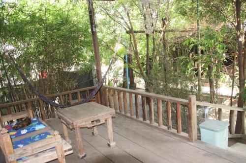 a porch with a hammock and a bench and trees at Fish Island Bungalows in Kampot