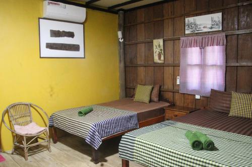 a room with two beds and a chair in it at Fish Island Bungalows in Kampot