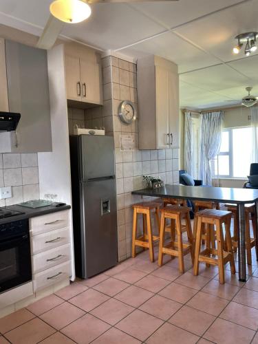 a kitchen with a table and chairs and a refrigerator at Jakaranda 22 apartment, Uvongo in Uvongo Beach