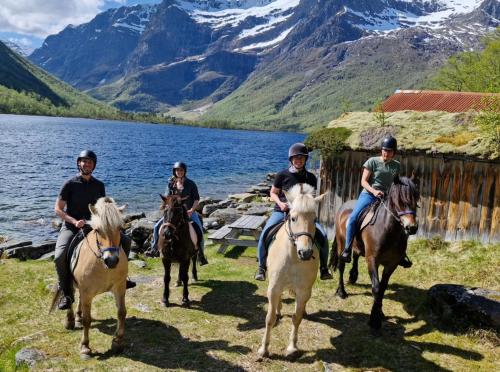 a group of people riding horses by a lake at Stall Rygg Mountain Cottage, Gloppen 