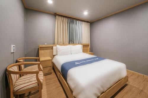 a small bedroom with a bed and a chair at Morning Calm Jeju in Jeju