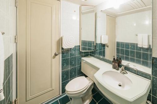 a bathroom with a sink and a toilet and a mirror at Morning Calm Jeju in Jeju