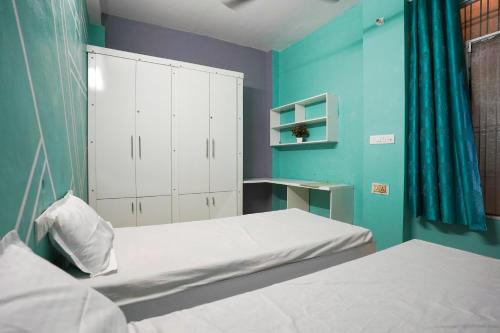 a bedroom with two beds and a blue wall at Akshay BnB & HomeStay in Lucknow