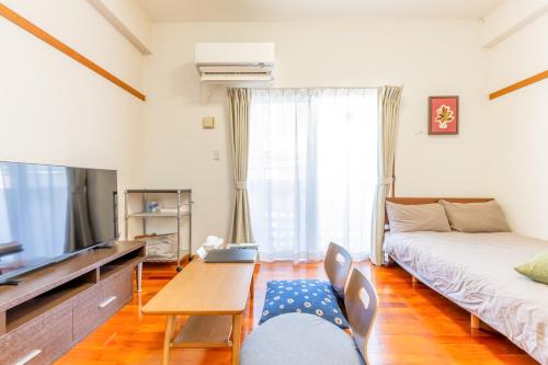 a living room with a bed and a tv at Casa Leo ASATO カサレオ安里 in Naha