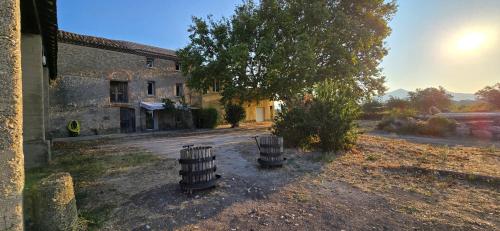 an old building with two wooden barrels in a yard at Studio 2 Personnes avec piscine in Jonquières