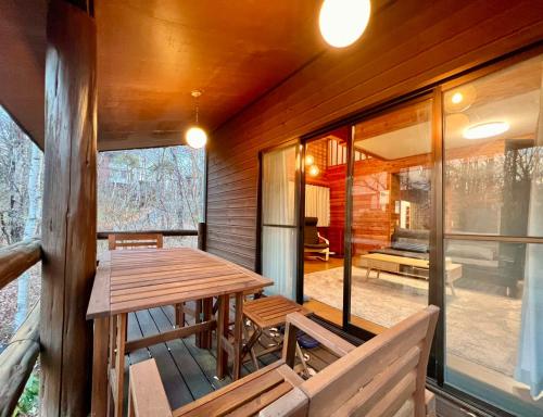 a room with a wooden table and benches on a porch at 花の街1079# Nature Escape BBQ in Tsumagoi