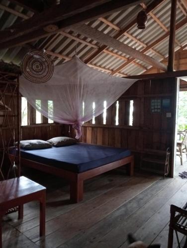 a bedroom with a bed with a mosquito net at Koh Thmei Resort in Phumĭ Kâng Kéng