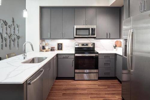 a kitchen with stainless steel appliances and gray cabinets at AMLI Addison in Addison