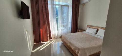 a bedroom with a bed and a large window at Goga Guest House in Kvariati