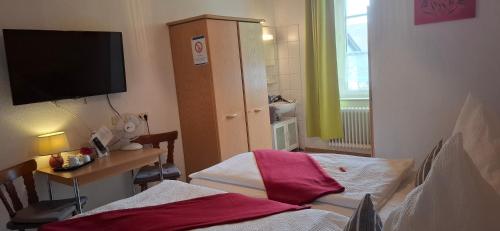 a room with two beds and a tv on the wall at Gasthaus Schwanen in Oberkirch