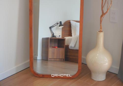 a mirror with a vase and a white vase at QR Hotel Dalat in Xuan An