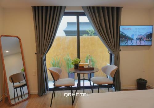 a room with a table and chairs and a large window at QR Hotel Dalat in Xuan An