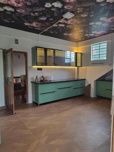 a kitchen with green cabinets and a painted ceiling at Ïa-Ki Homestay in Shillong