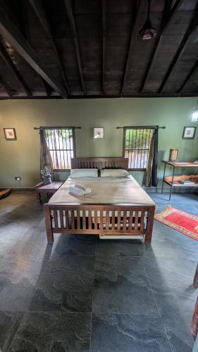 a large wooden bed in a room with windows at 501 Thumpalai Road in Point Pedro