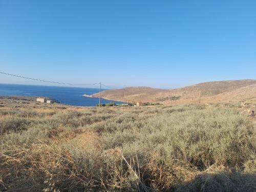 a field with the ocean in the background at Akrotirio Tainaro House in Marmari