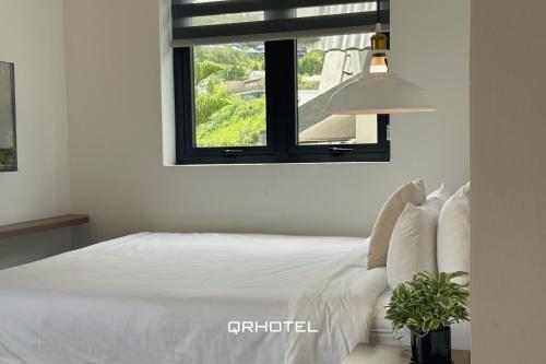 a bedroom with a white bed and a window at QR Hotel Dalat in Xuan An