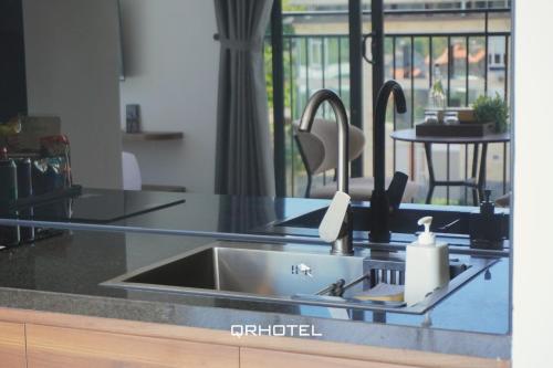 a kitchen counter with a sink and a table at QR Hotel Dalat in Xuan An