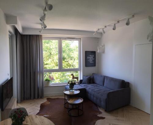 a living room with a couch and a window at Apartament Kolska in Warsaw