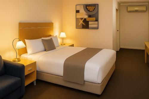 una habitación de hotel con una cama y una silla en The Heritage Bendigo, en Bendigo
