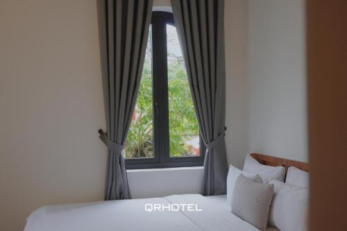 a bedroom with a bed and a window at QR Hotel Dalat in Xuan An