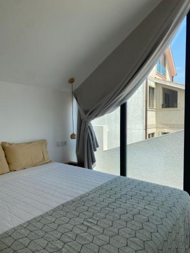 a bedroom with a bed and a large window at Apartamento Centola julio y agost min 7N in Cangas de Morrazo