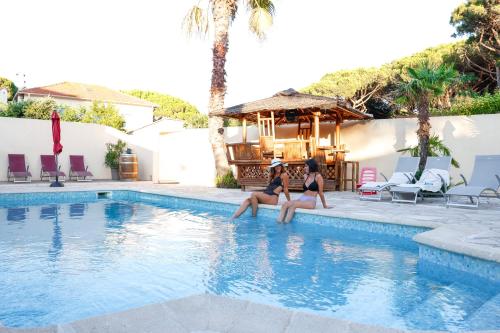 deux femmes assises au bord d'une piscine dans l'établissement Rêve D'azur, Mazet en bord de mer, parking, Piscine partagée, Terrasse BBQ & draps inclus la Nartelle, 1 salon, 1 chambre, 1 cuisine , 1 sdb, à Sainte-Maxime