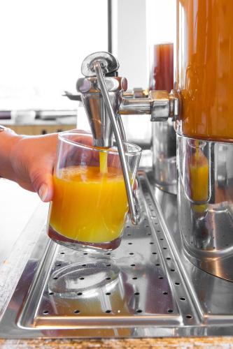 Eine Person presst Orangensaft in einem Entsafter. in der Unterkunft Le Relais des Iles in Coudeville