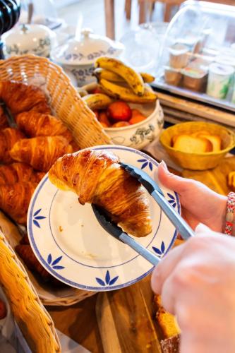 Eine Person, die einen Teller mit Essen, darunter ein Croissant, in der Hand hält. in der Unterkunft Le Relais des Iles in Coudeville