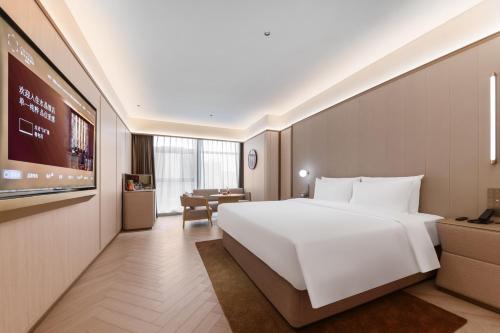 a hotel room with a large white bed and a table at Crystal Hotel Guangzhou Huadu in Huadu