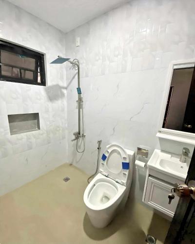 a white bathroom with a toilet and a sink at The Hidden Escape in Sampong