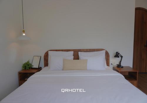 a bedroom with a bed with white sheets and pillows at QR Hotel Dalat in Xuan An