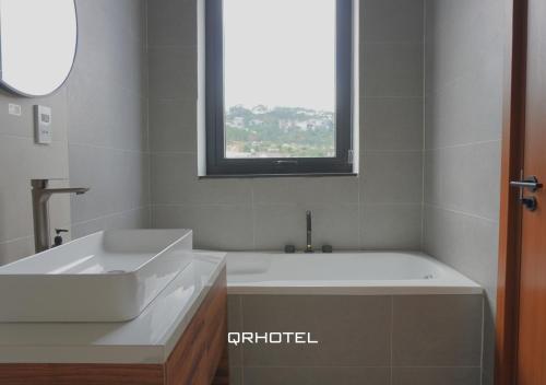 a bathroom with a tub and a sink and a window at QR Hotel Dalat in Xuan An