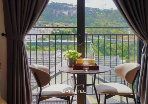 a balcony with a table and chairs and a window at QR Hotel Dalat in Xuan An