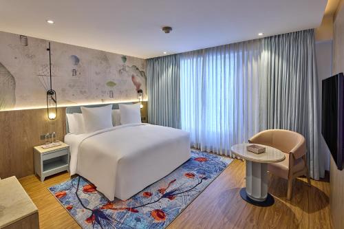 a bedroom with a white bed and a table and a desk at ICONIQA Hotel Mumbai International Airport in Mumbai