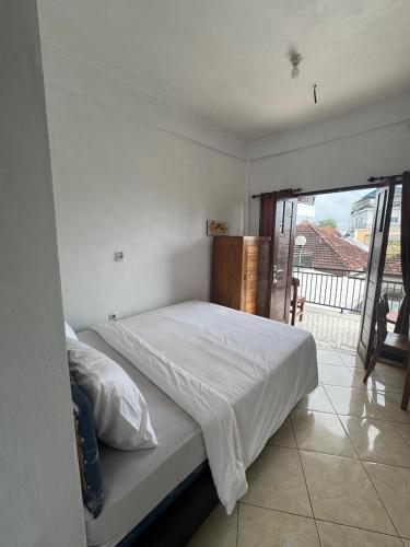 a white bed in a bedroom with a balcony at Canggu 77 Guest House in Badung