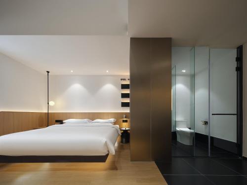 a bedroom with a large white bed and a bathroom at SFEEL设计师酒店Designer Hotel成都太古里春熙路步行街店 in Chengdu