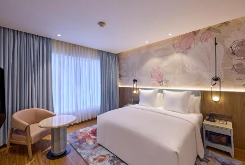 a hotel room with a large white bed and a table at ICONIQA Hotel Mumbai International Airport in Mumbai