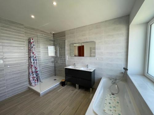 a bathroom with a tub and a sink and a mirror at Ty Gwer proche des plages de Pors Carn & La Torche - 8 personnes in Penmarcʼh