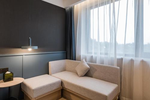 a living room with a couch and a window at Atour Light Hotel Temple of Heaven in Beijing