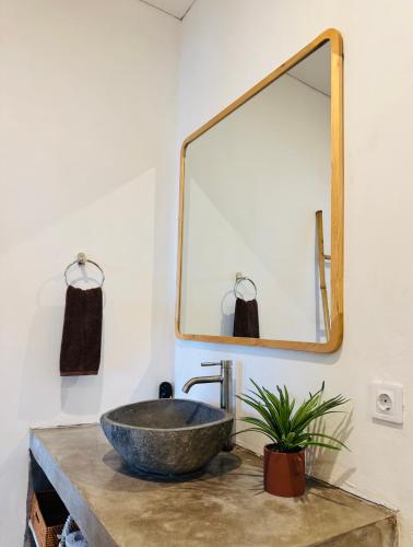 a bathroom with a stone sink and a mirror at Whãnau villa 1 in Cemagi
