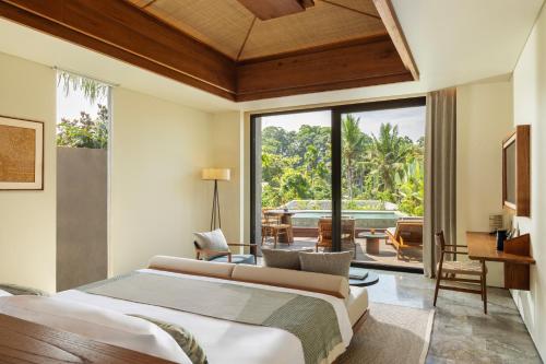 a bedroom with a bed and a view of a pool at Alaya Suites Ubud in Ubud