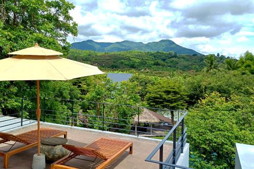 a patio with an umbrella and two chairs and a table at Chombua MaeWang ชมบัว in Chiang Mai