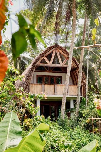 a resort building with a thatched roof and palm trees at Villa Monyet Java in Batukaras